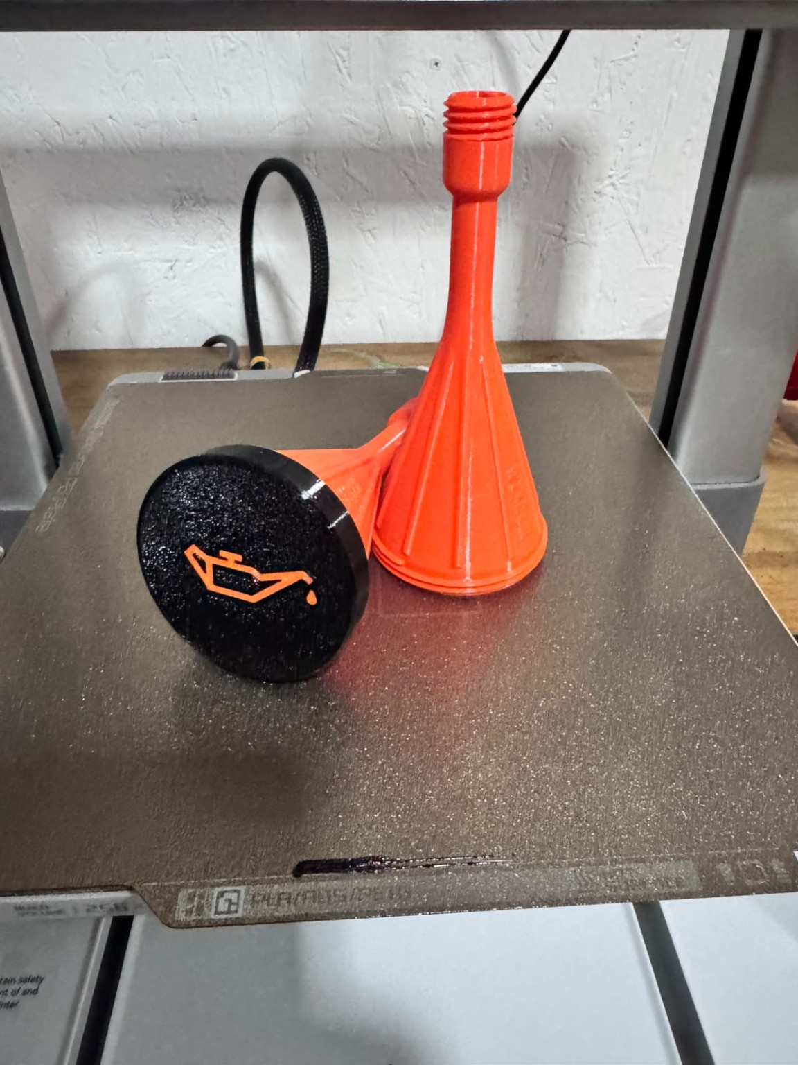 Embudos naranjas impresos en 3D y tapa negra con símbolo de aceite